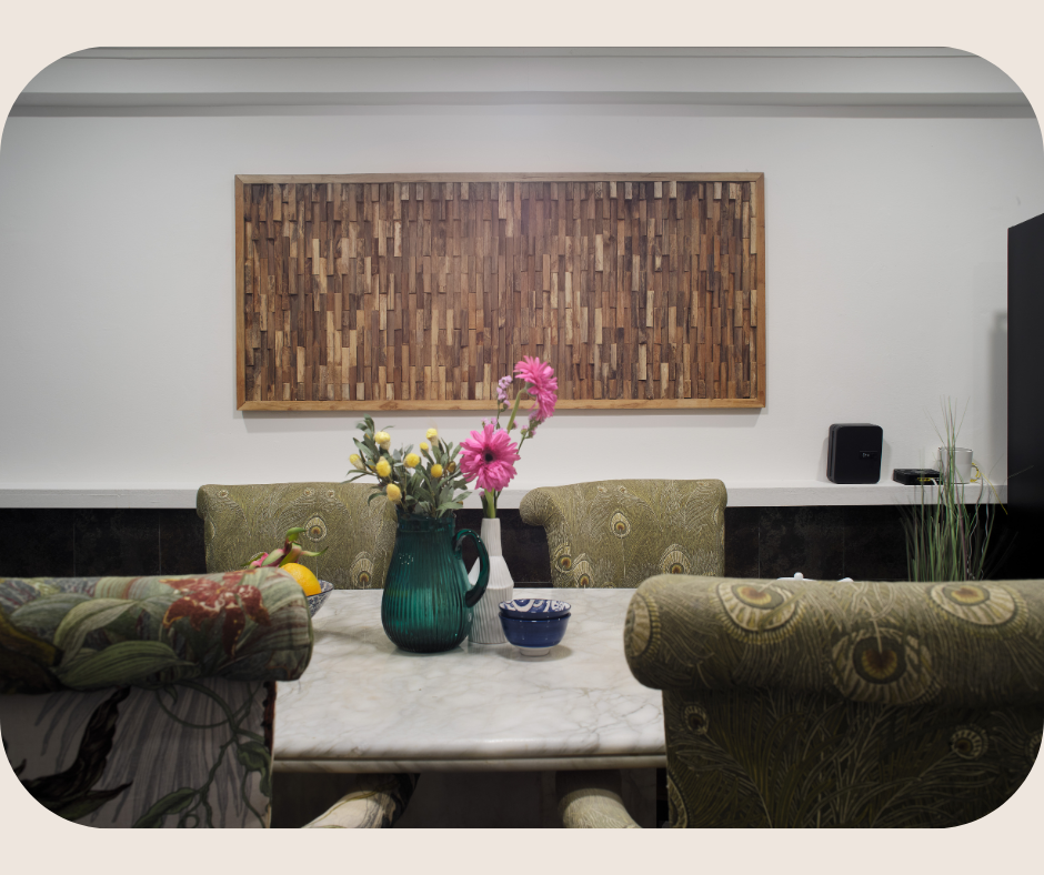 Elegant dining area with a marble table, upholstered chairs, floral centerpiece, and textured wooden wall art, reflecting refined Living in Bukit Timah.
